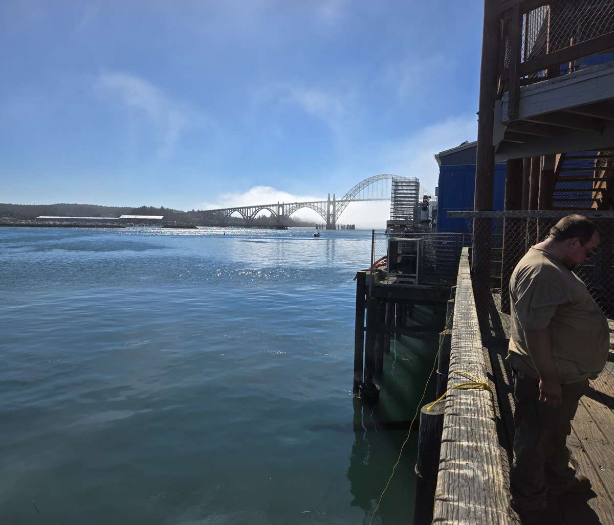 Waterfront buildings beside a bay, with a bridge in the distance.