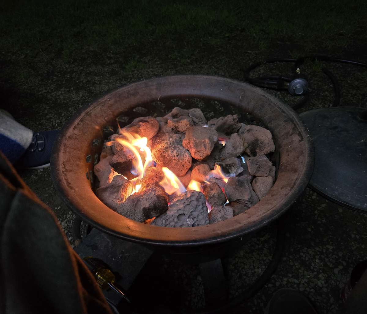 Flames glowing among rocks in a round gas fire ring after dark.